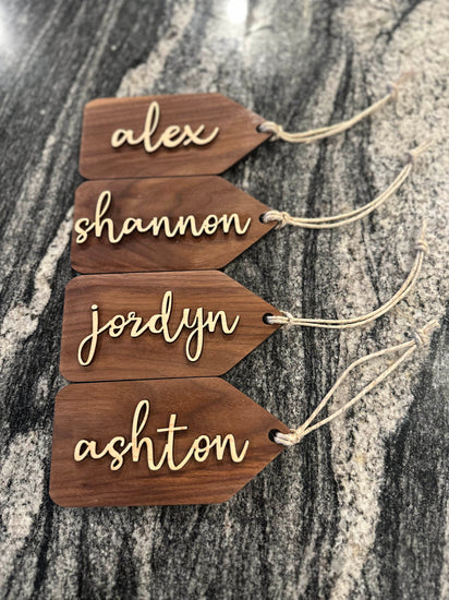 Wooden name tags/ stocking tags hanging on a Christmas tree with decorative lights.