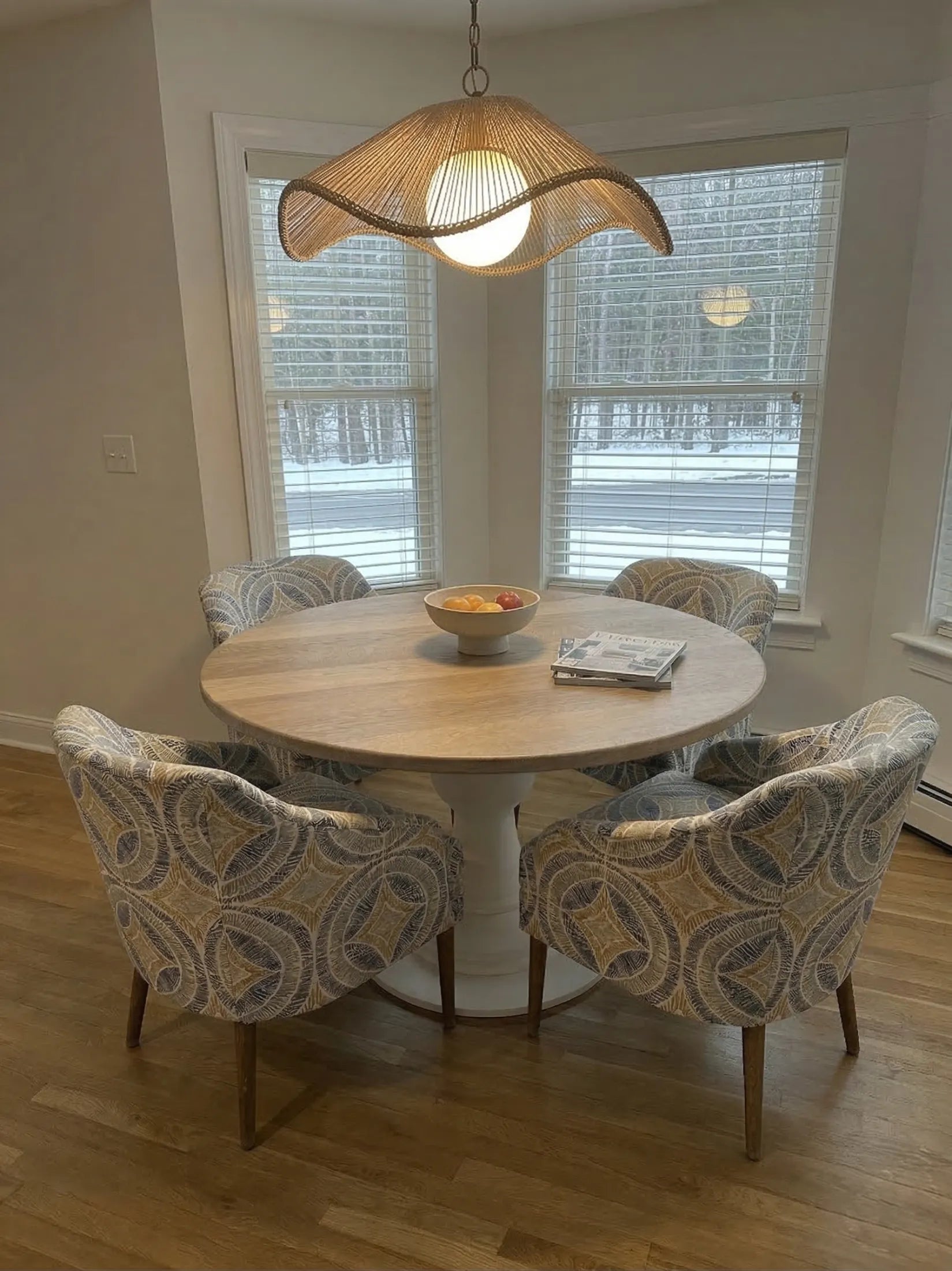 A round oak dining table with a white pedestal and four chairs