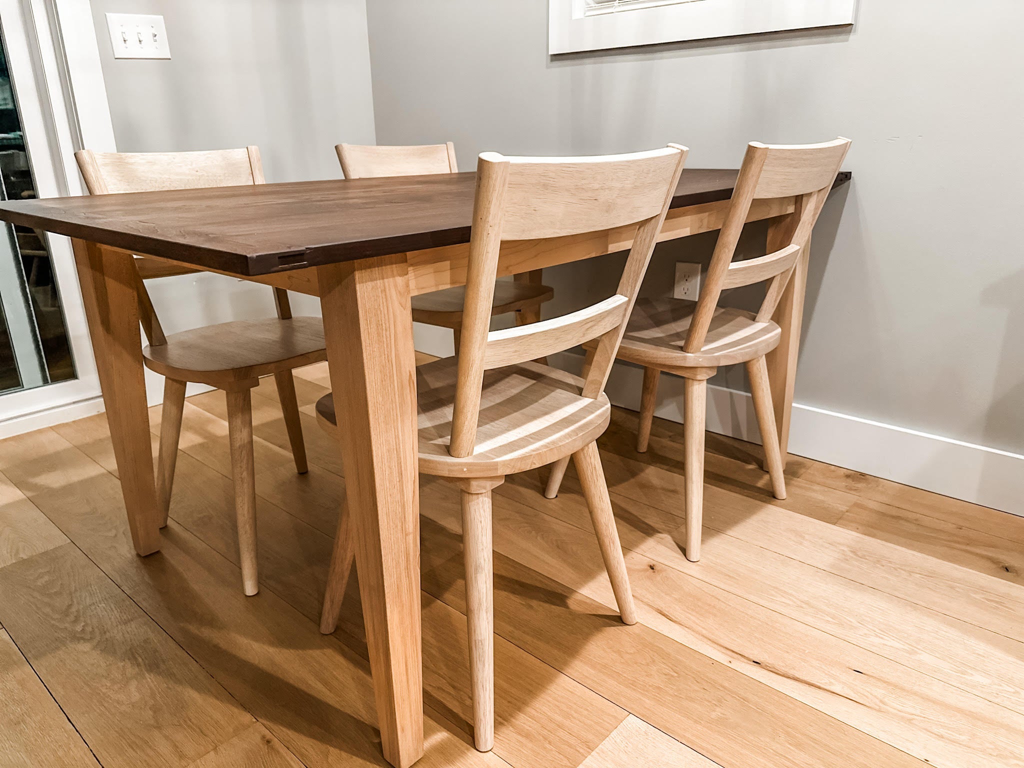 A walnut dining table with breadboard ends and a light maple base
